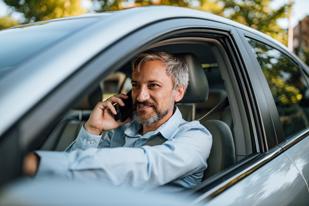 A middle aged man driving his used car