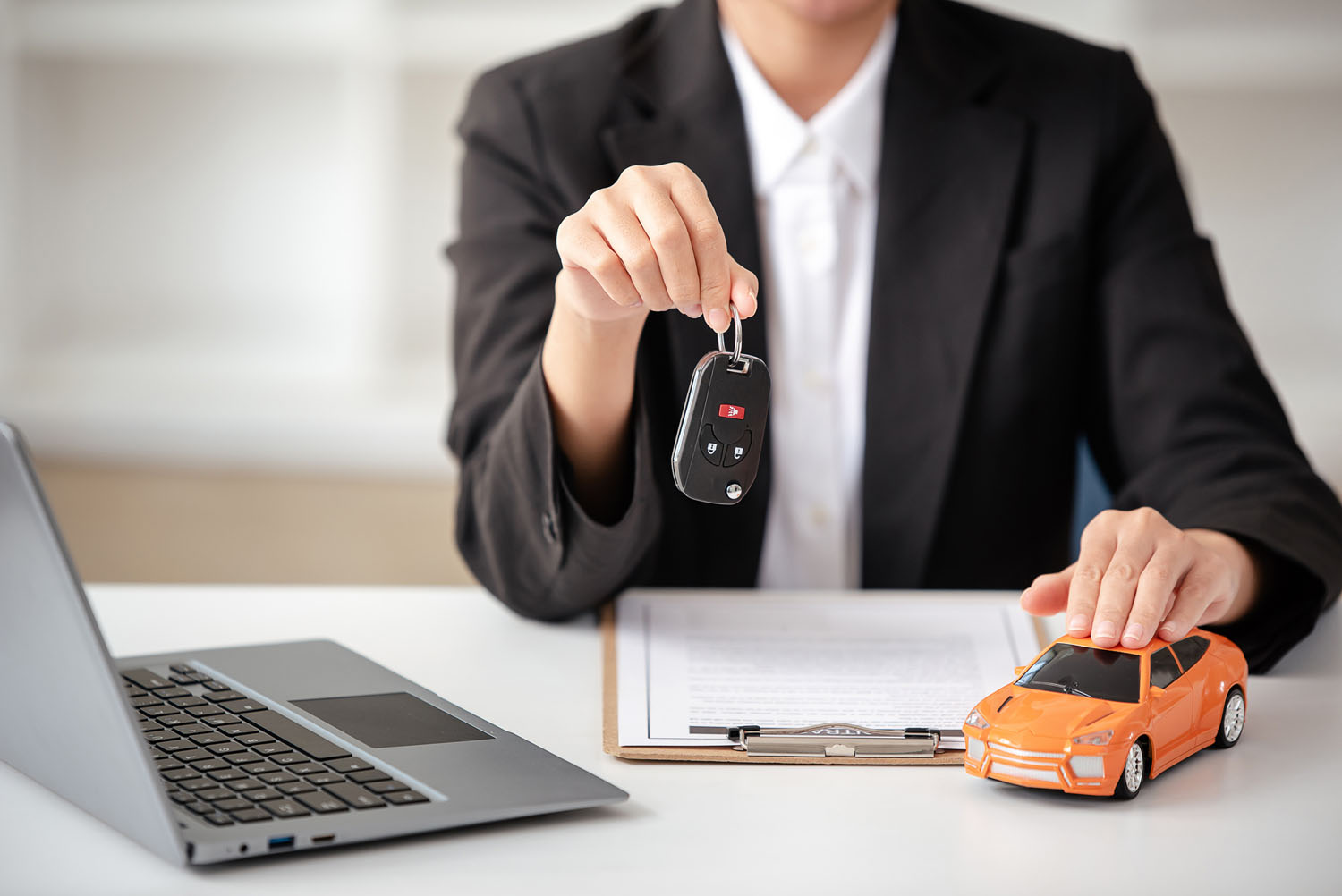 A woman sitting at a computer holds the keys to her new car