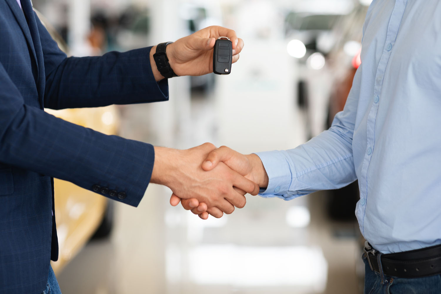 A car salesperson hands a customer the keys to a vehicle