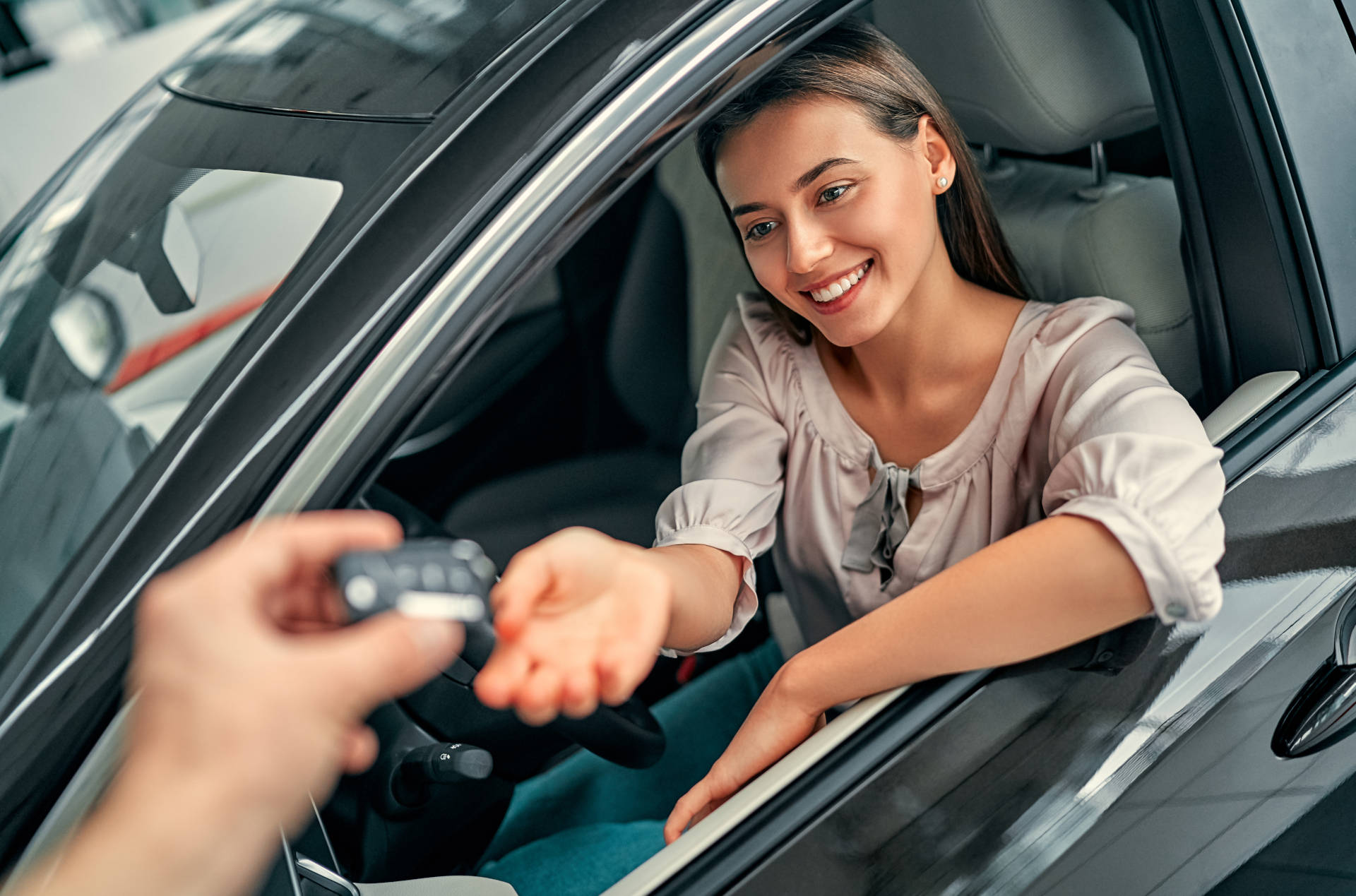 A smiling woman about to drive off in her used car.