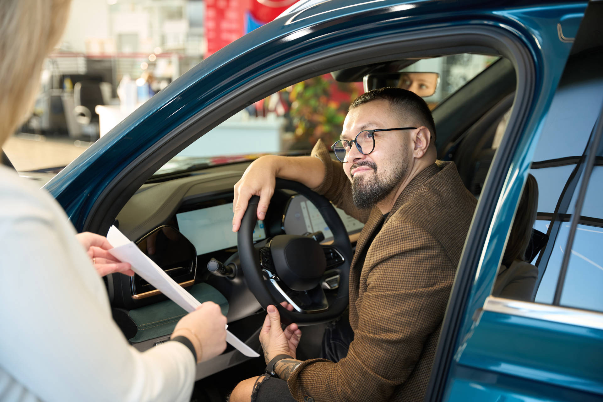 A man speaks with a saleswoman while buying a used car.